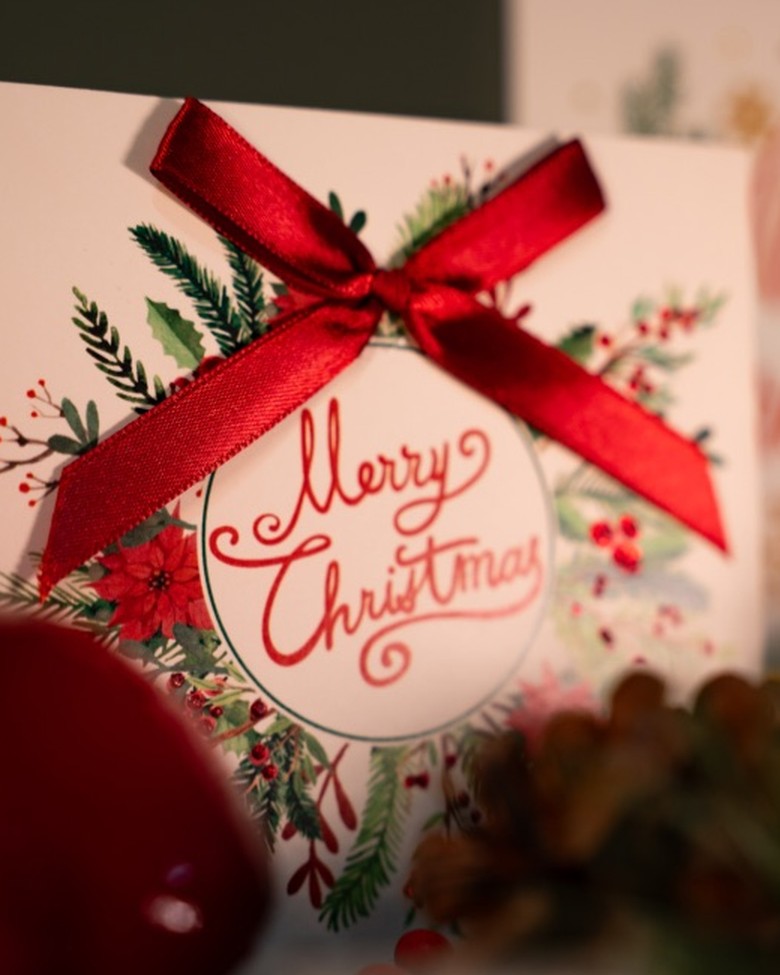 Świąteczna kartka z czerwoną kokardą i napisem Merry Christmas